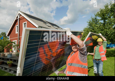 Workmen delivering solar panel house garden Stock Photo