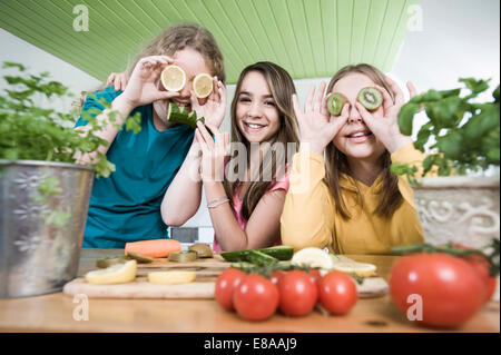 Girls in kitchen making faces with fruit Stock Photo