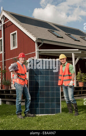 Workmen holding solar panel garden house Stock Photo