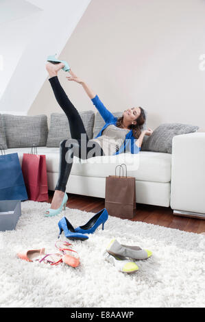 Young happy woman sitting on couch at home with her new high heels Stock Photo