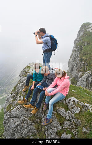 Father teenage kids using iPad in mountains Stock Photo