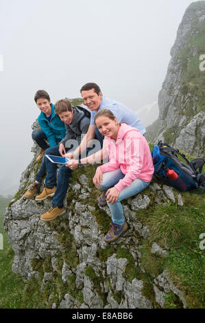 Father teenage kids using iPad in mountains Stock Photo