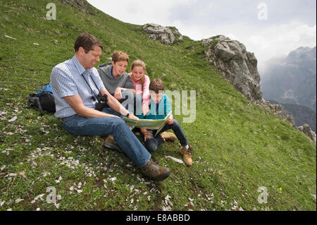 Father and kids looking at hiking map in Alps Stock Photo