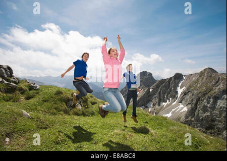 Girl and teenage boys jumping in air Alps Stock Photo