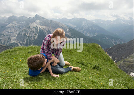 Young girl and boy playing wrestling on grass Alps Stock Photo