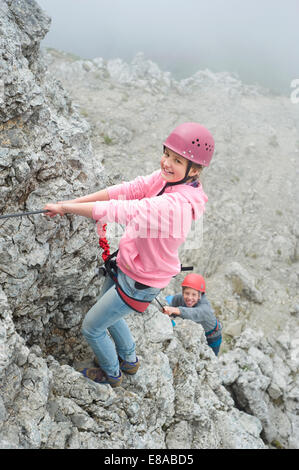 Brother sister climbing rock face mountains rope Stock Photo