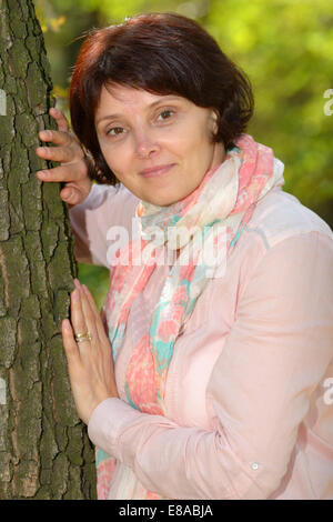 portrait of woman leaning against tree Stock Photo