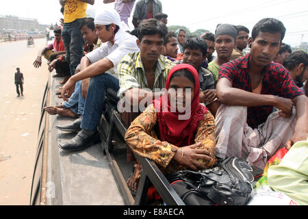 Dhaka-Tangail highway, Bangladesh. 3rd October, 2014. Bangladeshi people sit atop a bus prior to travelling across the country to celebrate Eid Al Adha festival on 03 October 2014. Dhaka-Tangail highway on Friday shows the road packed with buses and other vehicles overcrowded with home-goers. At least 3 million people leave the capital city to meet their relatives in their home villages for the Eid festival. Stock Photo