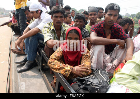 Dhaka-Tangail highway, Bangladesh. 3rd October, 2014. Bangladeshi people sit atop a bus prior to travelling across the country to celebrate Eid Al Adha festival on 03 October 2014. Dhaka-Tangail highway on Friday shows the road packed with buses and other vehicles overcrowded with home-goers. At least 3 million people leave the capital city to meet their relatives in their home villages for the Eid festival. Stock Photo