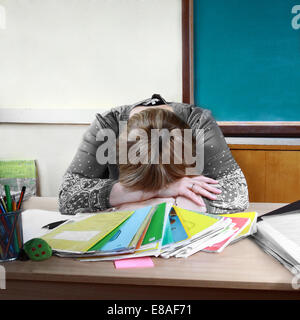 Teacher sits in classroom setting head on hands Stock Photo