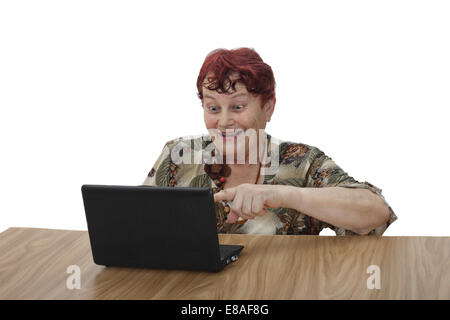 Senior woman with cheerful amazement points at notebook screen isolated on white background Stock Photo
