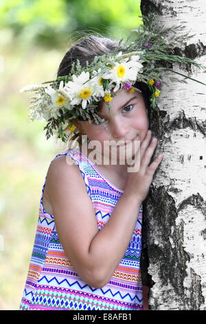 Girl with wreath on her head leaned against birch outdoor closeup Stock Photo