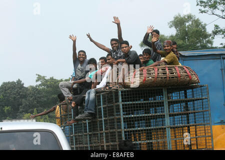 Dhaka-Tangail highway, Bangladesh. 3rd October, 2014. Bangladeshi people sit atop a bus prior to travelling across the country to celebrate Eid Al Adha festival on 03 October 2014. Dhaka-Tangail highway on Friday shows the road packed with buses and other vehicles overcrowded with home-goers. At least 3 million people leave the capital city to meet their relatives in their home villages for the Eid festival. Stock Photo