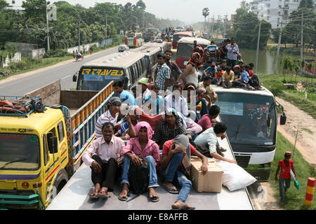 Dhaka-Tangail highway, Bangladesh. 3rd October, 2014. Bangladeshi people sit atop a bus prior to travelling across the country to celebrate Eid Al Adha festival on 03 October 2014. Dhaka-Tangail highway on Friday shows the road packed with buses and other vehicles overcrowded with home-goers. At least 3 million people leave the capital city to meet their relatives in their home villages for the Eid festival. Stock Photo