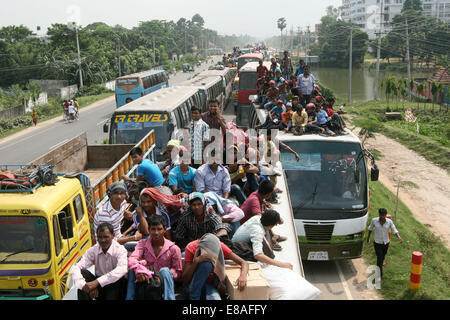 Dhaka-Tangail highway, Bangladesh. 3rd October, 2014. Bangladeshi people sit atop a bus prior to travelling across the country to celebrate Eid Al Adha festival on 03 October 2014. Dhaka-Tangail highway on Friday shows the road packed with buses and other vehicles overcrowded with home-goers. At least 3 million people leave the capital city to meet their relatives in their home villages for the Eid festival. Stock Photo