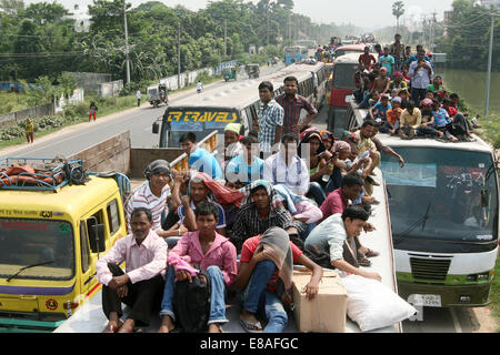 Dhaka-Tangail highway, Bangladesh. 3rd October, 2014. Bangladeshi people sit atop a bus prior to travelling across the country to celebrate Eid Al Adha festival on 03 October 2014. Dhaka-Tangail highway on Friday shows the road packed with buses and other vehicles overcrowded with home-goers. At least 3 million people leave the capital city to meet their relatives in their home villages for the Eid festival. Stock Photo