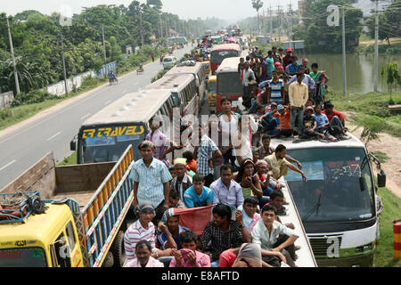 Dhaka-Tangail highway, Bangladesh. 3rd October, 2014. Bangladeshi people sit atop a bus prior to travelling across the country to celebrate Eid Al Adha festival on 03 October 2014. Dhaka-Tangail highway on Friday shows the road packed with buses and other vehicles overcrowded with home-goers. At least 3 million people leave the capital city to meet their relatives in their home villages for the Eid festival. Stock Photo