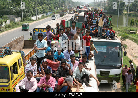 Dhaka-Tangail highway, Bangladesh. 3rd October, 2014. Bangladeshi people sit atop a bus prior to travelling across the country to celebrate Eid Al Adha festival on 03 October 2014. Dhaka-Tangail highway on Friday shows the road packed with buses and other vehicles overcrowded with home-goers. At least 3 million people leave the capital city to meet their relatives in their home villages for the Eid festival. Stock Photo