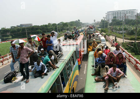 Dhaka-Tangail highway, Bangladesh. 3rd October, 2014. Bangladeshi people sit atop a bus prior to travelling across the country to celebrate Eid Al Adha festival on 03 October 2014. Dhaka-Tangail highway on Friday shows the road packed with buses and other vehicles overcrowded with home-goers. At least 3 million people leave the capital city to meet their relatives in their home villages for the Eid festival. Stock Photo