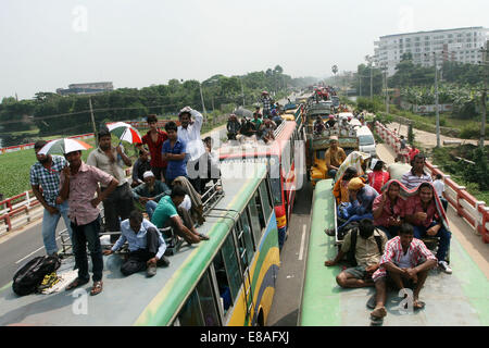 Dhaka-Tangail highway, Bangladesh. 3rd October, 2014. Bangladeshi people sit atop a bus prior to travelling across the country to celebrate Eid Al Adha festival on 03 October 2014. Dhaka-Tangail highway on Friday shows the road packed with buses and other vehicles overcrowded with home-goers. At least 3 million people leave the capital city to meet their relatives in their home villages for the Eid festival. Stock Photo