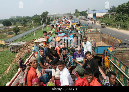 Dhaka-Tangail highway, Bangladesh. 3rd October, 2014. Bangladeshi people sit atop a bus prior to travelling across the country to celebrate Eid Al Adha festival on 03 October 2014. Dhaka-Tangail highway on Friday shows the road packed with buses and other vehicles overcrowded with home-goers. At least 3 million people leave the capital city to meet their relatives in their home villages for the Eid festival. Stock Photo