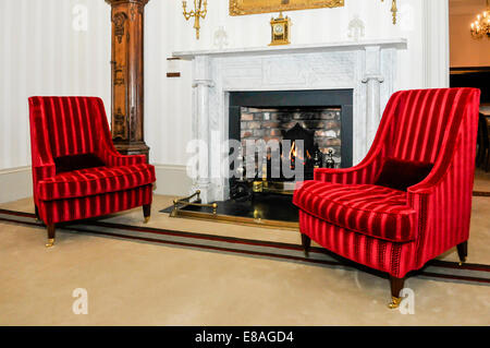 Two chairs beside a fireplace in a large, old fashioned house. Stock Photo