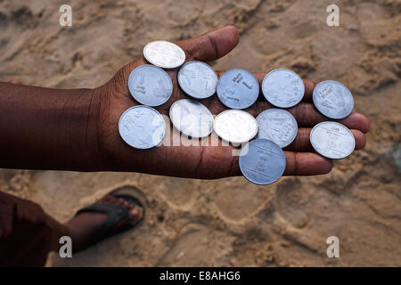 A young boy with Indian Rupees coins on his hand on the beach in Puri, India. Stock Photo