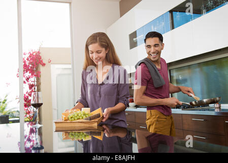 Couple preparing cheeseboard and cooking in kitchen Stock Photo