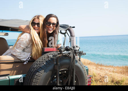 Portrait of two young women leaning out of jeep at coast, Malibu, California, USA Stock Photo