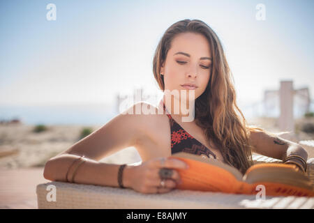 Young woman reading book at beach, Castiadas, Sardinia, Italy Stock Photo