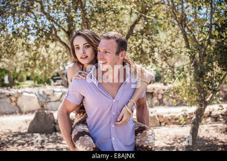Young man giving girlfriend piggyback ride, Castiadas, Sardinia, Italy