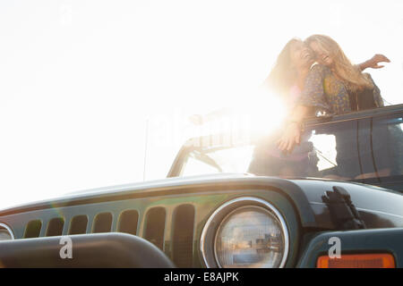 Two young women standing up in back of jeep Stock Photo
