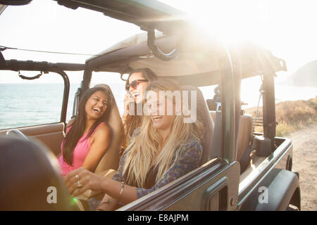 Three young women driving in jeep at coast, Malibu, California, USA Stock Photo