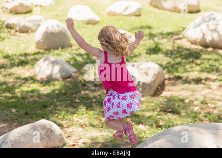 Young girl jumping from boulders in park Stock Photo