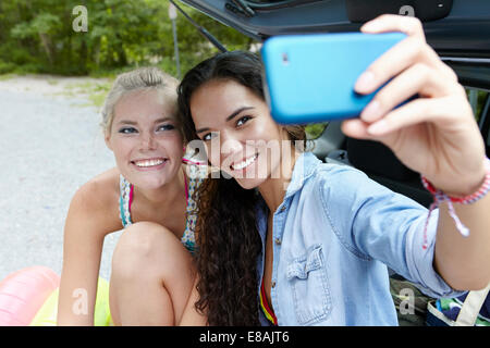 Hikers sitting at rear of car taking selfie Stock Photo