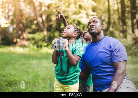 Young father with son and daughter bird watching in eco forest camp