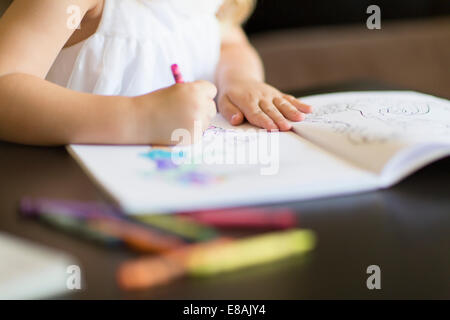 Cropped shot of girl coloring in book with crayons Stock Photo