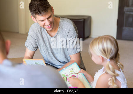 Male couple and daughter threading picture books in sitting room Stock Photo