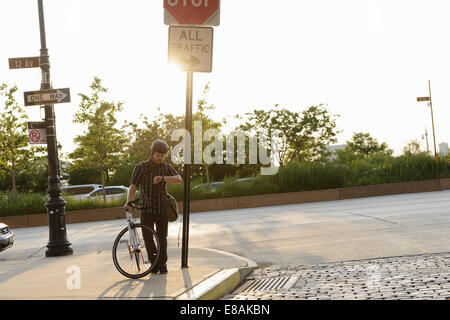Male cycle messenger checking time on roadside