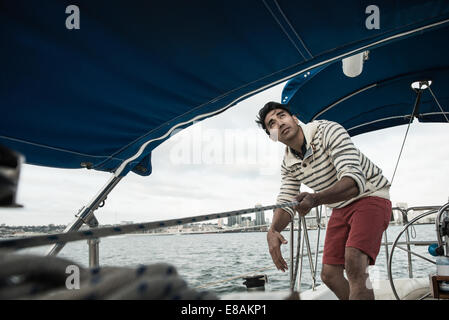 Young man looking up on sailing boat Stock Photo