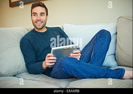 Man using digital tablet on sofa Stock Photo