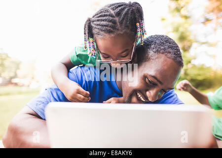 Father looking at digital tablet with daughter at eco camp