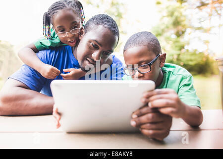 Father looking at digital tablet with daughter and son at eco camp