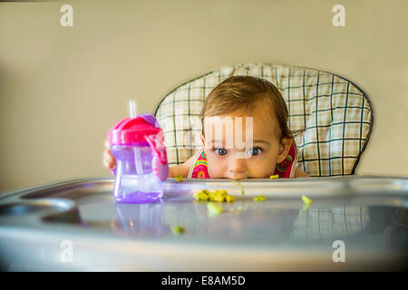 Portrait of shy baby girl in high chair Stock Photo