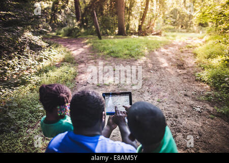 Father with daughter and son navigating with digital tablet in forest eco camp
