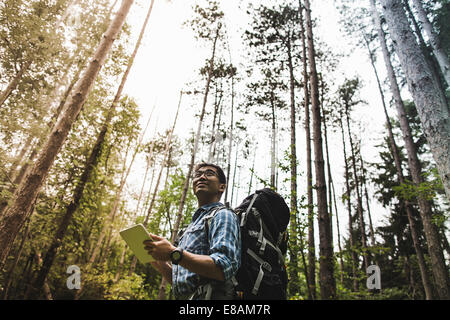 Hiker in forest using digital tablet