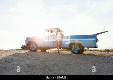 Portrait of young female surfer leaning against pickup truck at beach, Encinitas, California, USA Stock Photo