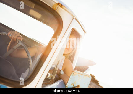 Young female surfer looking out from pickup truck window Stock Photo