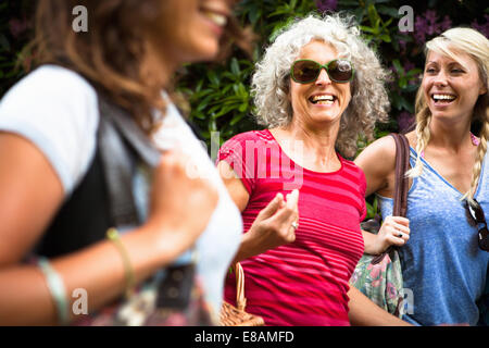 Mature mother and two daughters laughing and chatting whilst walking Stock Photo