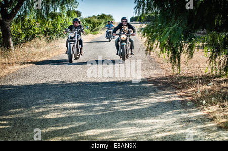 Four friends and one dog riding motorcycles on rural road, Cagliari, Sardinia, Italy Stock Photo